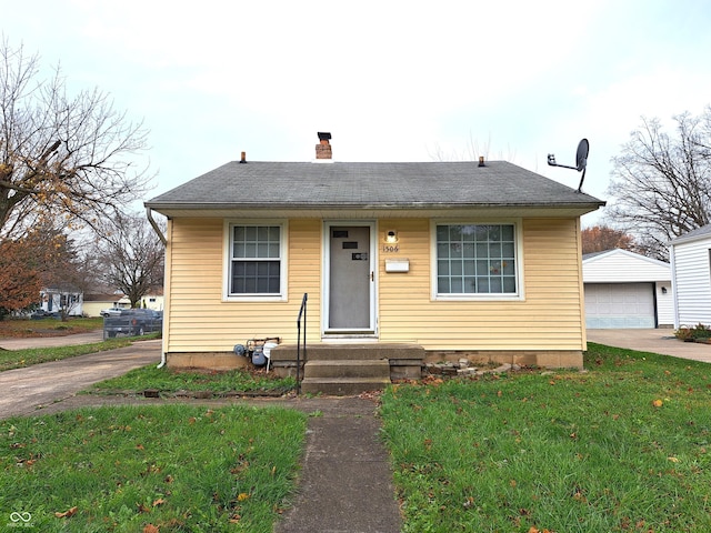 bungalow-style home with a garage, a front lawn, and an outdoor structure