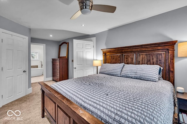 bedroom featuring ceiling fan, light colored carpet, and ensuite bath