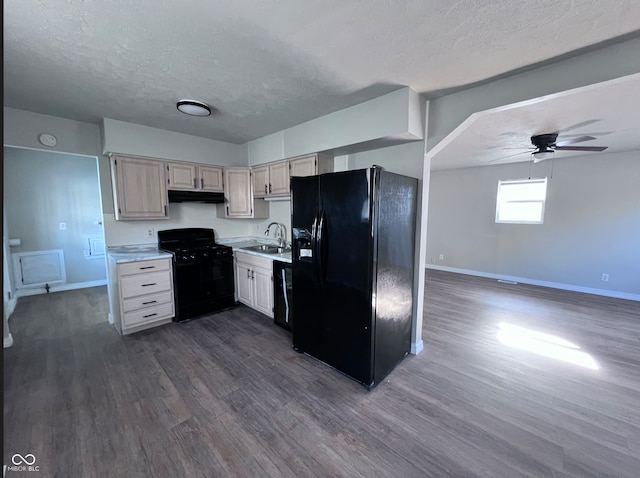 kitchen with under cabinet range hood, light countertops, black appliances, a ceiling fan, and a sink