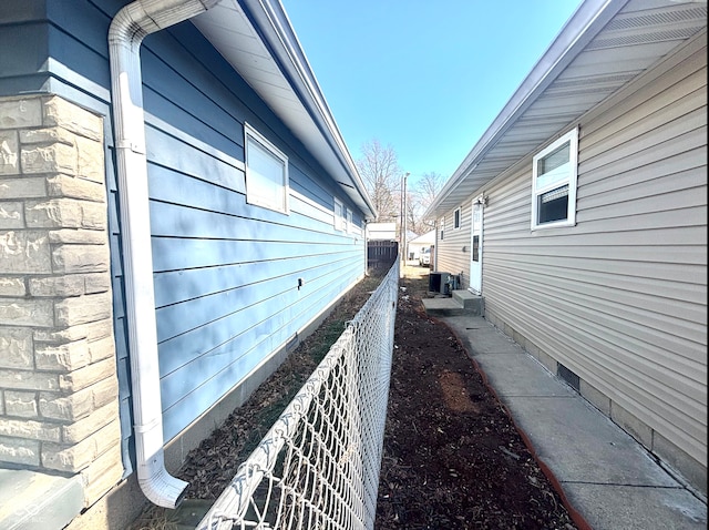 view of side of home with cooling unit and fence