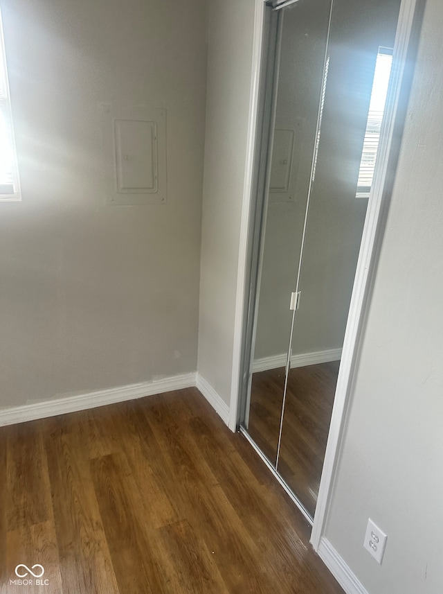 unfurnished bedroom featuring baseboards, a closet, and dark wood-style flooring