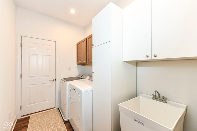 laundry area featuring dark wood-type flooring, washer and dryer, cabinets, and sink