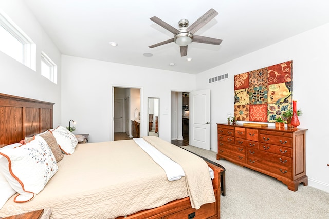 bedroom with ceiling fan, light colored carpet, and connected bathroom