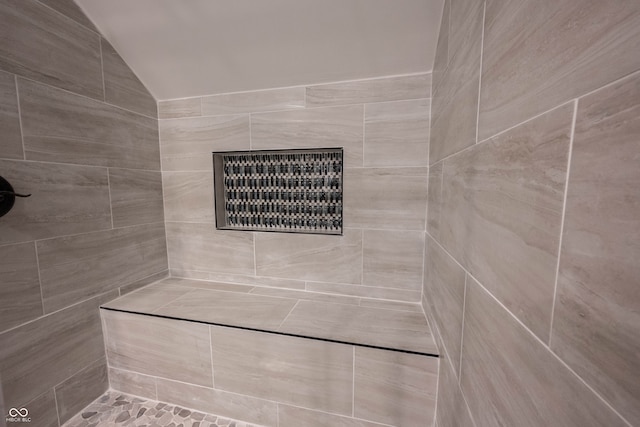 bathroom with a tile shower and vaulted ceiling