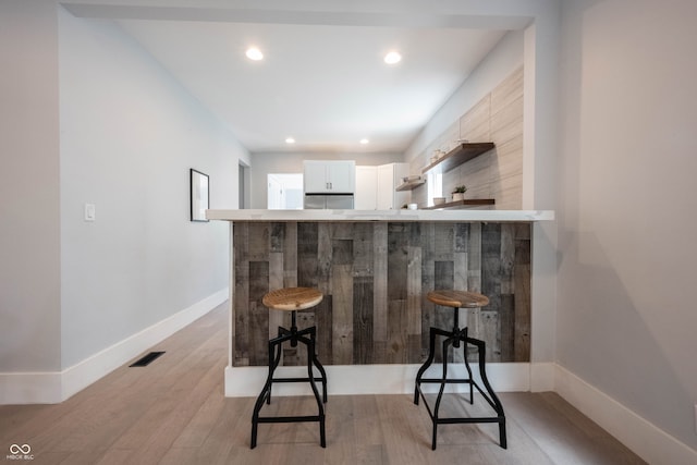 bar with white cabinetry and light hardwood / wood-style flooring