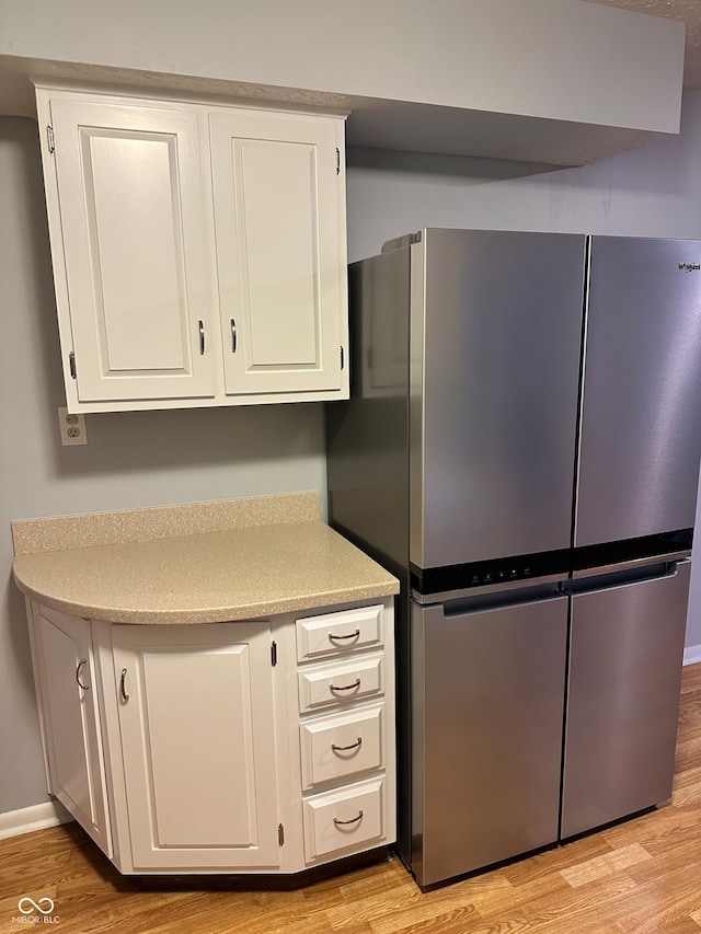 kitchen featuring white cabinets, stainless steel fridge, and light hardwood / wood-style flooring