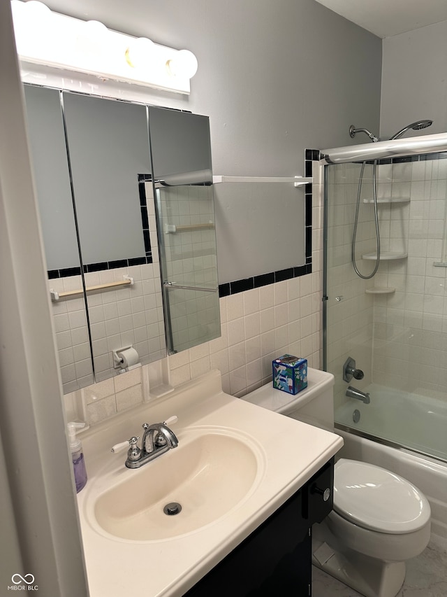 full bathroom featuring vanity, bath / shower combo with glass door, tile patterned flooring, toilet, and tile walls