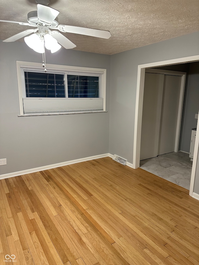 unfurnished bedroom featuring ceiling fan, a closet, and light wood-type flooring