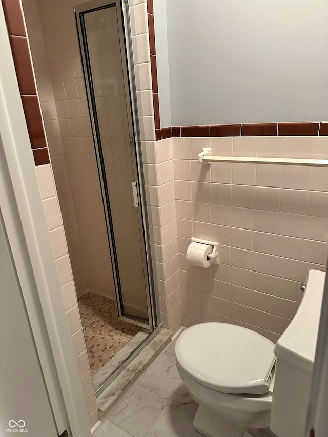 bathroom with a shower with shower door, tile walls, and toilet