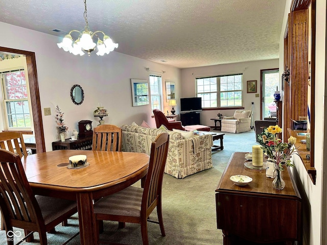 dining room with a textured ceiling, light colored carpet, and an inviting chandelier