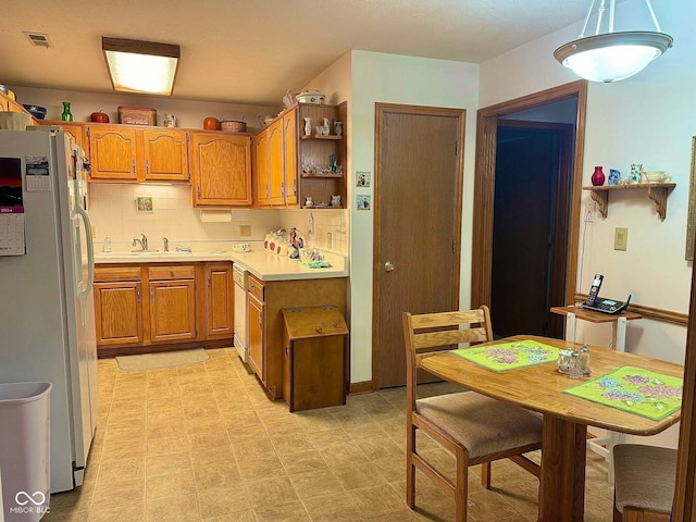 kitchen with decorative backsplash, pendant lighting, white appliances, and sink