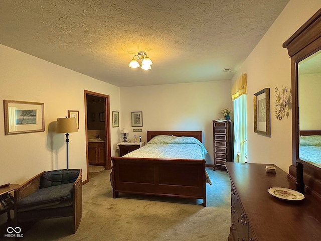 carpeted bedroom featuring ensuite bath, a textured ceiling, and an inviting chandelier