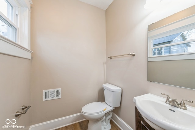 bathroom featuring hardwood / wood-style flooring, a healthy amount of sunlight, toilet, and sink