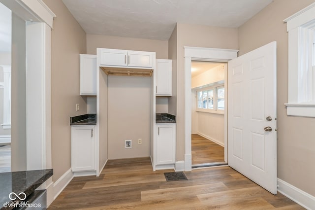 kitchen featuring dark stone counters, white cabinets, and light hardwood / wood-style floors