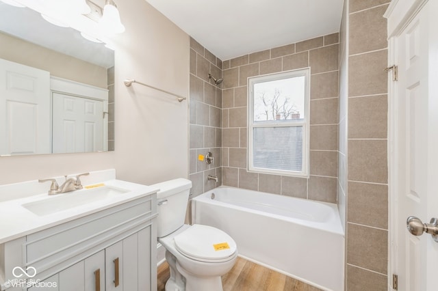 full bathroom featuring tiled shower / bath, hardwood / wood-style floors, vanity, and toilet