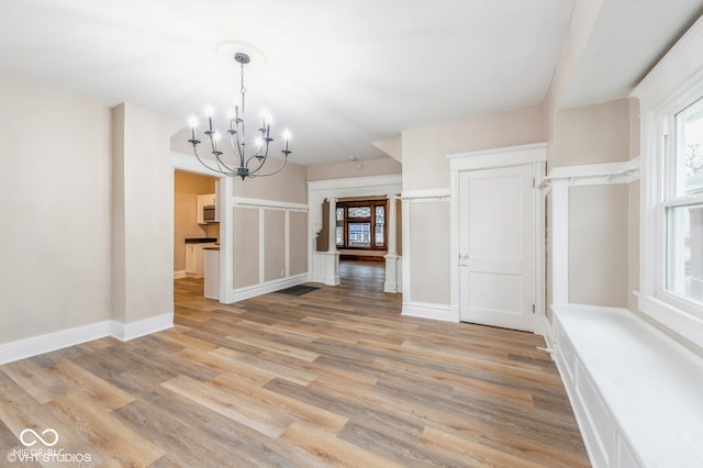 unfurnished dining area with light hardwood / wood-style floors and an inviting chandelier