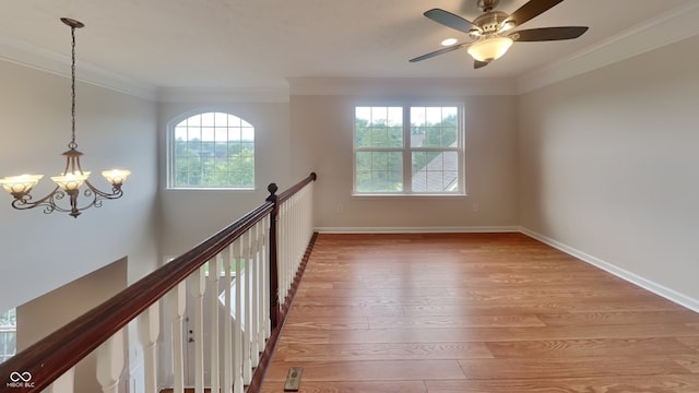 spare room featuring ceiling fan with notable chandelier, light wood-type flooring, and ornamental molding