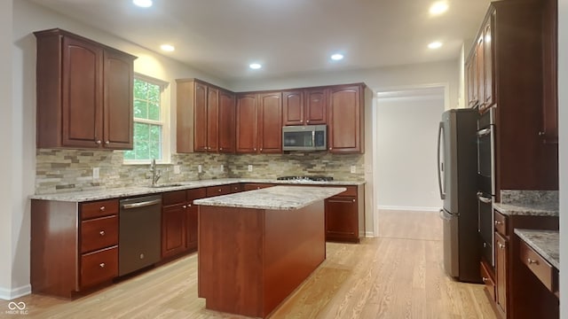 kitchen featuring sink, light wood-type flooring, tasteful backsplash, a kitchen island, and stainless steel appliances