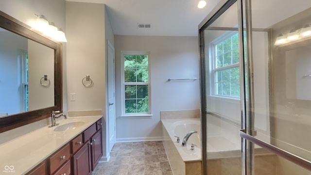 bathroom with a bathing tub, vanity, and a healthy amount of sunlight