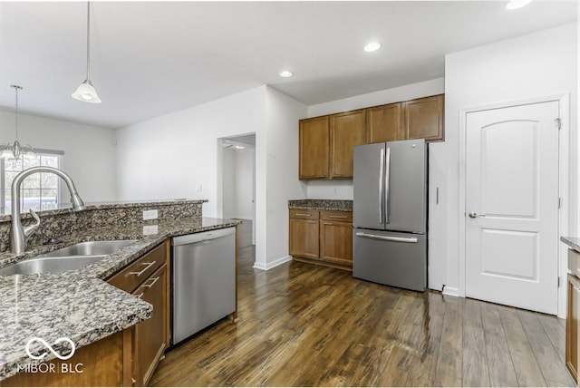 kitchen featuring sink, stainless steel appliances, dark stone countertops, and pendant lighting