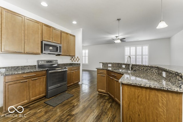 kitchen with a healthy amount of sunlight, stainless steel appliances, decorative light fixtures, and dark stone countertops