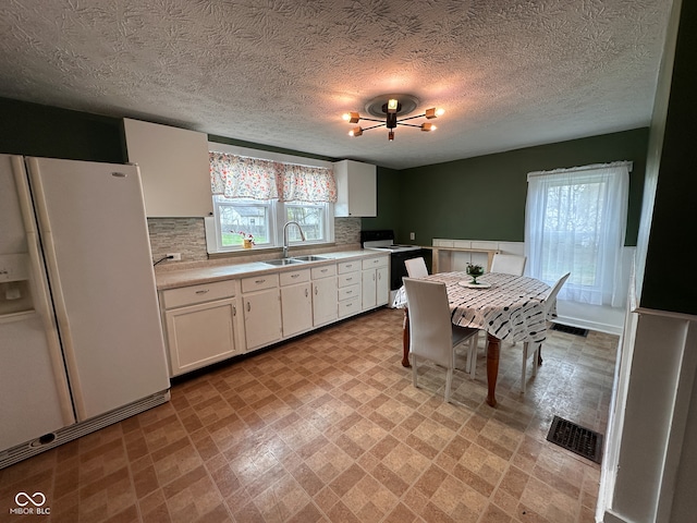 kitchen featuring decorative backsplash, a textured ceiling, white appliances, sink, and white cabinetry