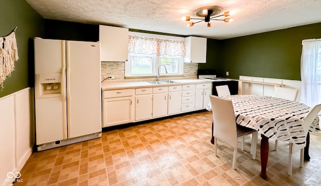 kitchen with white appliances, an inviting chandelier, white cabinets, sink, and decorative backsplash