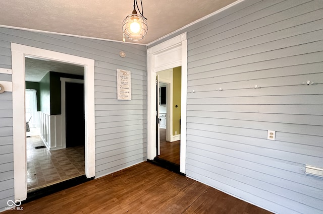 spare room featuring vaulted ceiling, wood walls, dark hardwood / wood-style floors, and ornamental molding