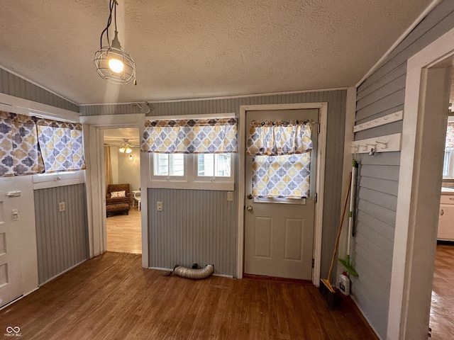 doorway to outside with hardwood / wood-style floors, a textured ceiling, crown molding, and wood walls