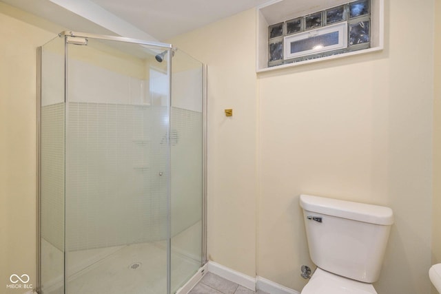 bathroom featuring tile patterned flooring, toilet, and a shower with door