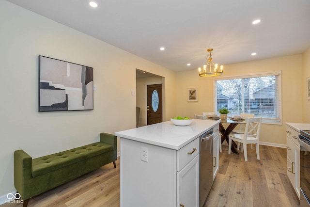 kitchen with white cabinets, decorative light fixtures, a kitchen island, and light wood-type flooring