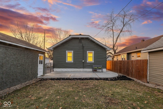 back house at dusk with a yard and a patio