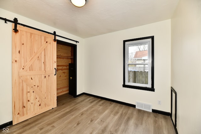 unfurnished bedroom featuring a barn door and hardwood / wood-style floors