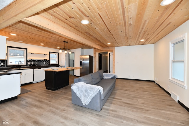 kitchen featuring a center island, decorative light fixtures, stainless steel fridge, and light wood-type flooring