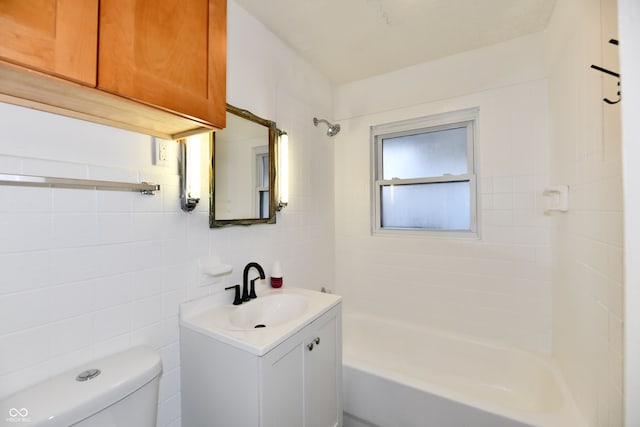 full bathroom with vanity, toilet, tiled shower / bath, and tile walls