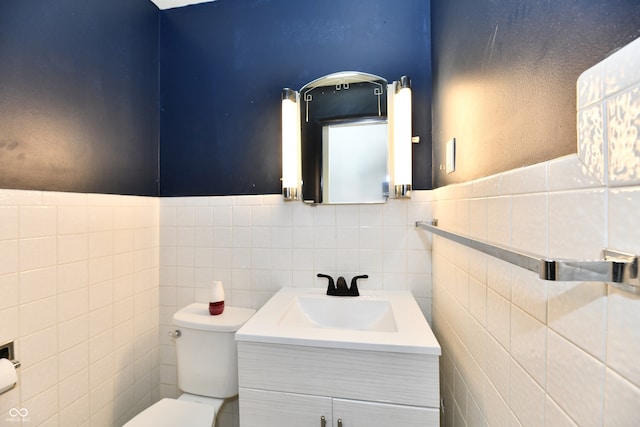 bathroom with vanity, toilet, and tile walls