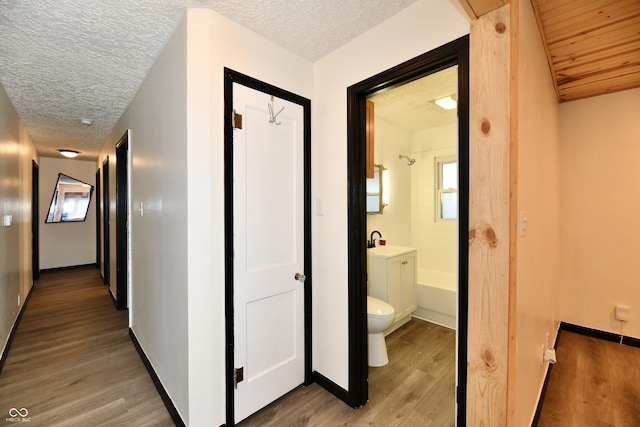 corridor featuring light hardwood / wood-style flooring, a textured ceiling, and sink