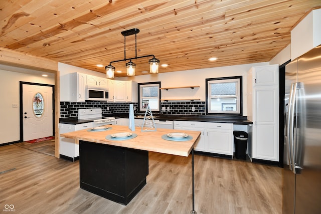 kitchen featuring white appliances, white cabinets, a kitchen island, decorative light fixtures, and light hardwood / wood-style floors