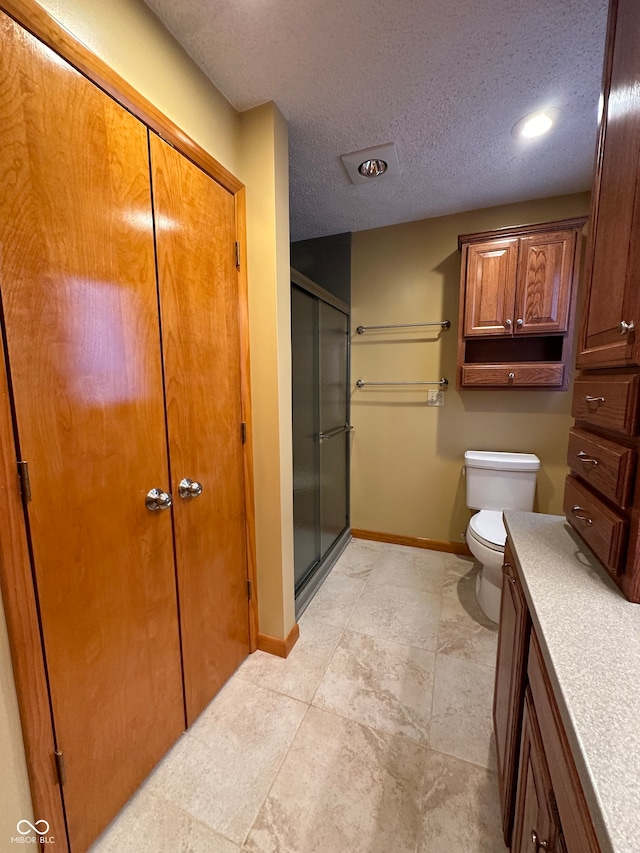 bathroom featuring toilet, vanity, a textured ceiling, and walk in shower