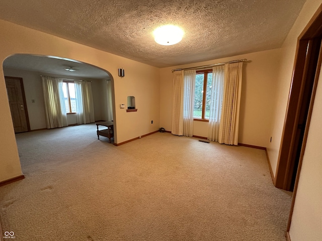 carpeted spare room featuring plenty of natural light and a textured ceiling