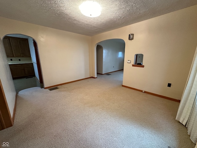 spare room featuring light colored carpet and a textured ceiling