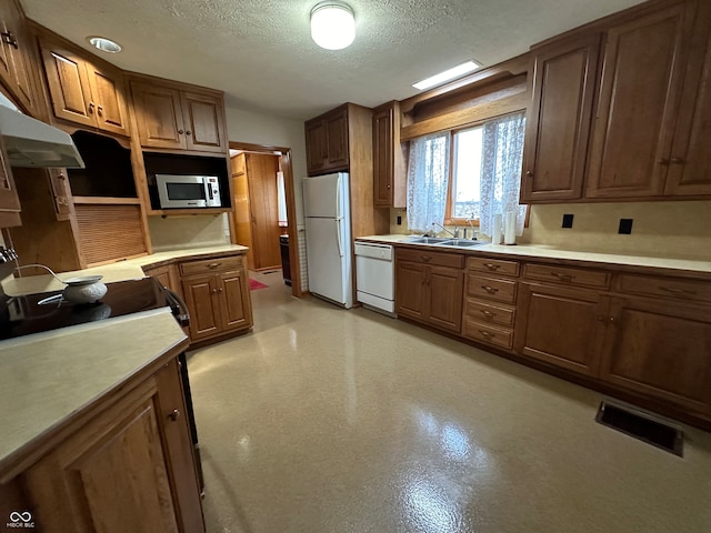 kitchen featuring a textured ceiling, white appliances, and sink