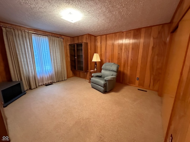 unfurnished room with carpet floors, a textured ceiling, and wooden walls