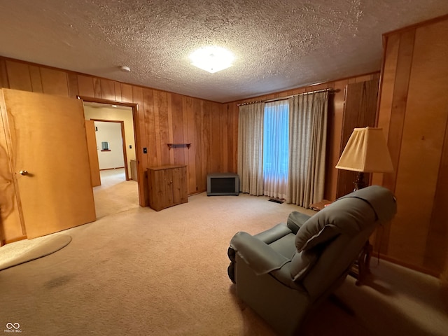 living area featuring wood walls, light carpet, and a textured ceiling