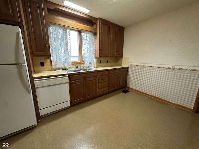 kitchen featuring a textured ceiling, white appliances, and sink