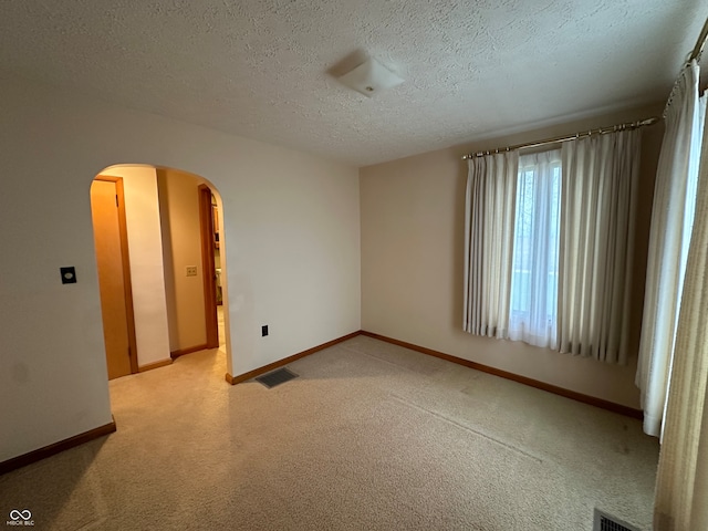 carpeted empty room featuring a textured ceiling