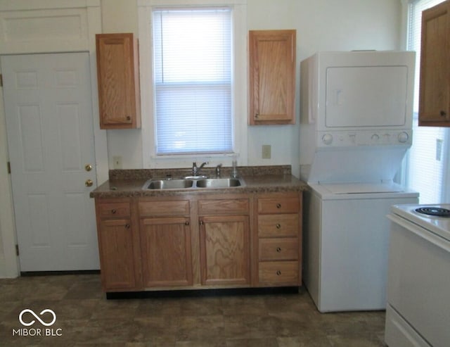 kitchen featuring white stove, plenty of natural light, stacked washer and clothes dryer, and sink