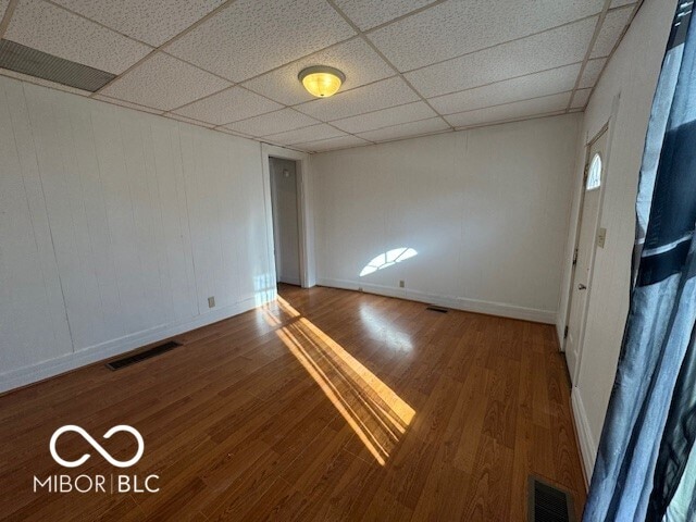 unfurnished room with hardwood / wood-style floors and a drop ceiling