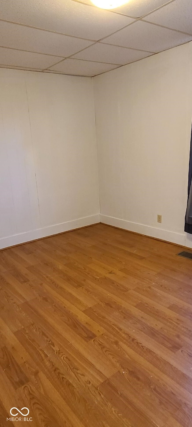 unfurnished room featuring hardwood / wood-style floors and a drop ceiling