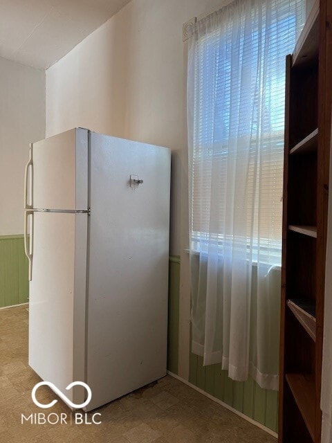 kitchen with white fridge and wooden walls